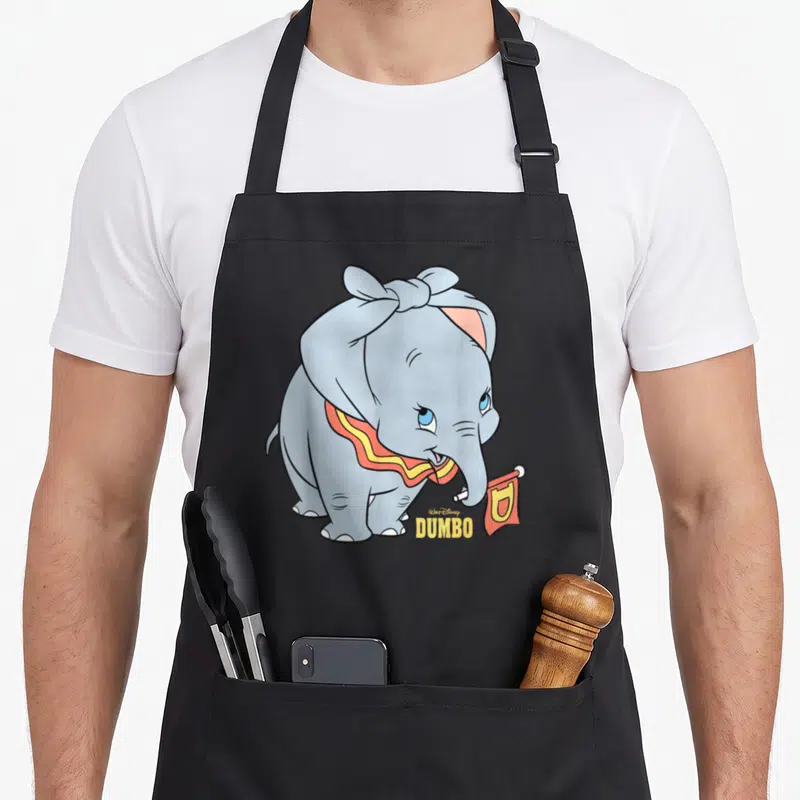 Tablier de cuisine noir avec l'éléphant Dumbo tenant un petit drapeau rouge orné d'un D jaune.