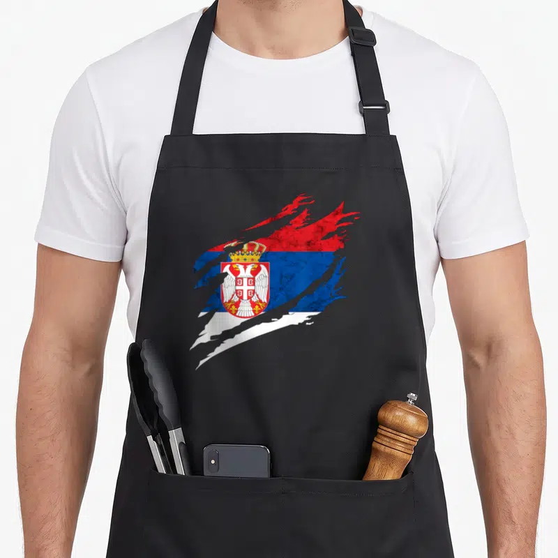 Tablier de cuisine noir avec drapeau serbe stylisé en traits de pinceau et aigle bicéphale couronné au centre.