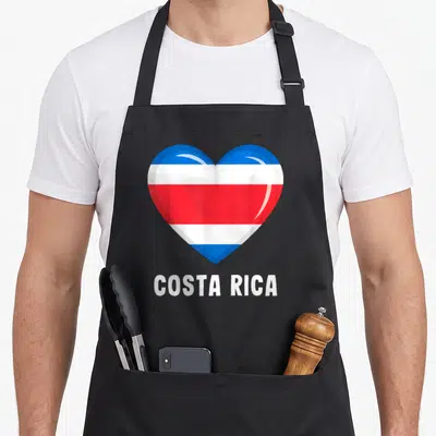 Tablier de cuisine noir avec un grand cœur aux couleurs du drapeau de Costa Rica et le nom du pays imprimé en dessous.