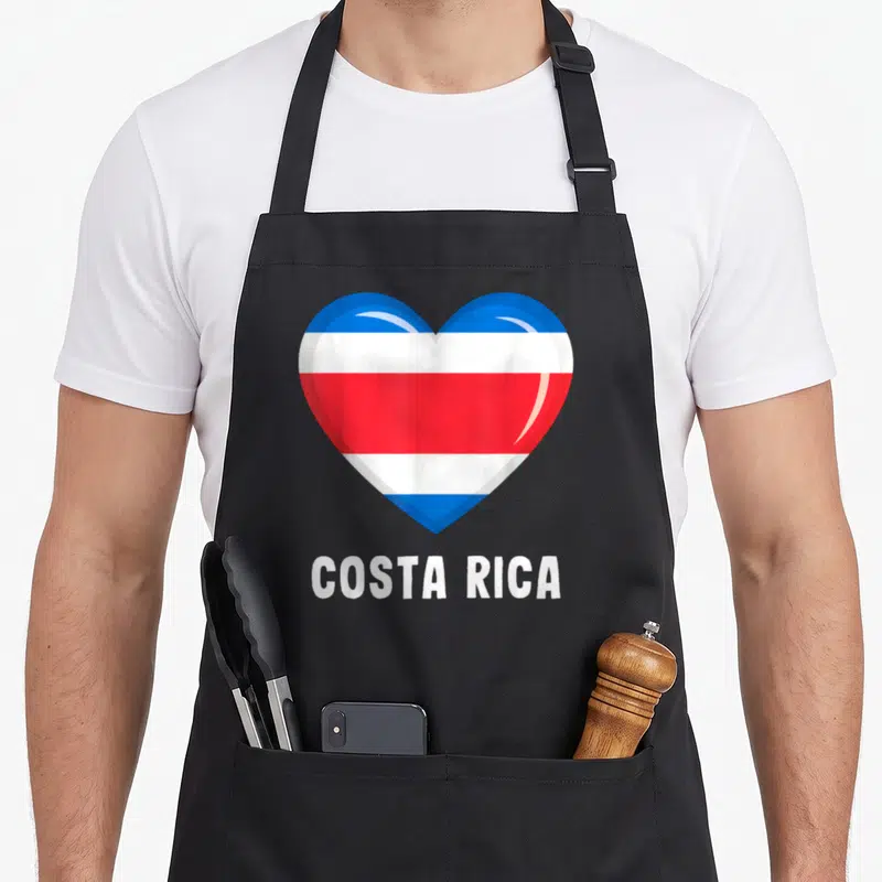 Tablier de cuisine noir avec un grand cœur aux couleurs du drapeau de Costa Rica et le nom du pays imprimé en dessous.