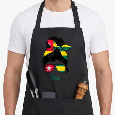 Tablier de cuisine noir avec une femme aux lunettes et foulard aux couleurs du drapeau du Togo et le mot Togo en bas.