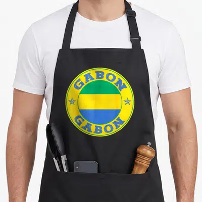 Tablier de cuisine noir avec un emblème circulaire jaune portant le drapeau du Gabon et le texte Gabon en bleu.