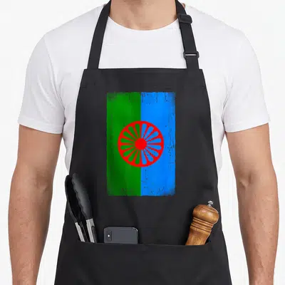 Tablier de cuisine noir avec drapeau Romani vert bleu et roue rouge stylisée au centre.