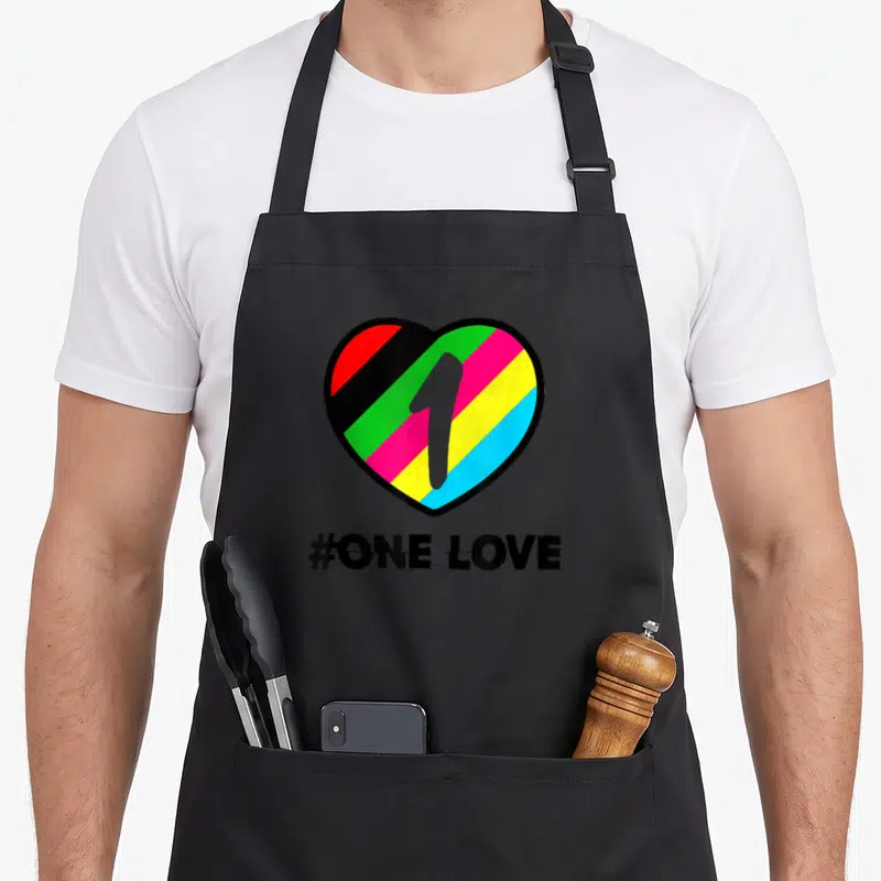 Tablier de cuisine noir avec un grand cœur multicolore contenant le chiffre 1 et le texte #ONE LOVE en dessous.