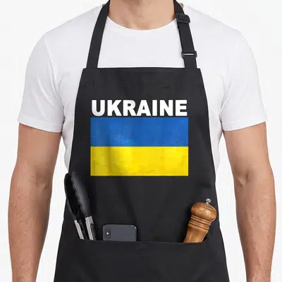 Tablier de cuisine noir avec drapeau Ukraine bleu et jaune texturé et inscription UKRAINE en blanc.