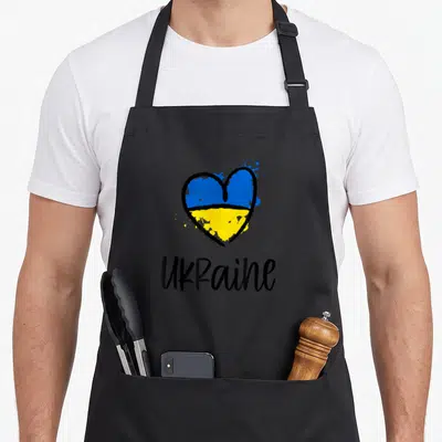 Tablier de cuisine noir avec un cœur bicolore bleu et jaune et le mot UKraine écrit en noir.