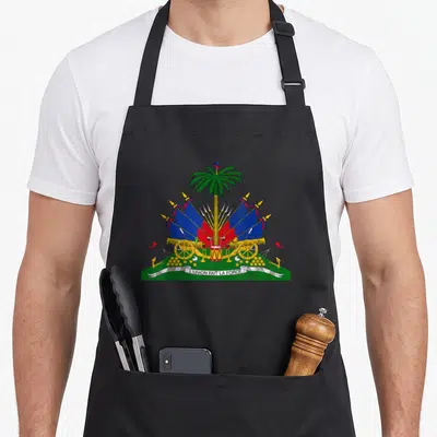 Tablier de cuisine noir avec le drapeau haïtien, un palmier, des canons dorés et le texte l'union fait la force sur une banderole blanche.