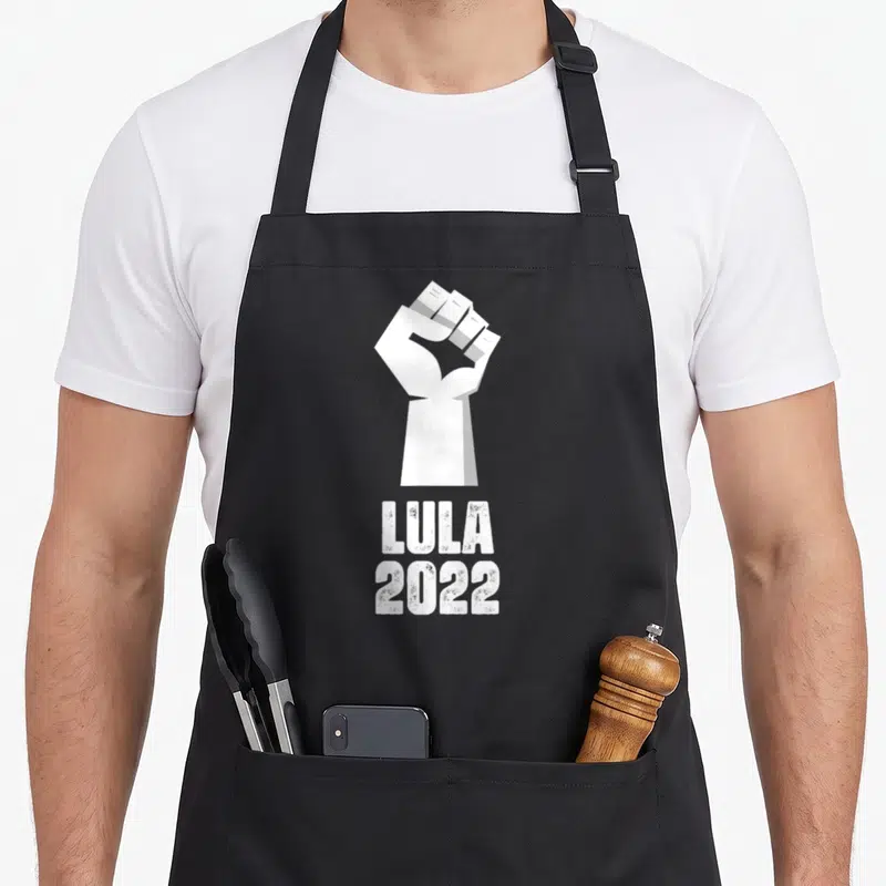 Tablier de cuisine noir avec un poing levé blanc et les mots Lula 2022 imprimés en dessous.