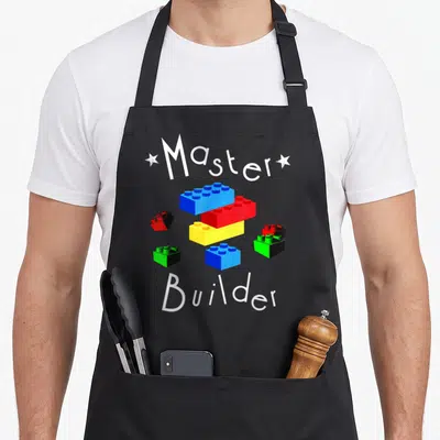 Tablier de cuisine noir avec des blocs de construction bleus, rouges, jaunes et verts autour des mots Master Builder en blanc.