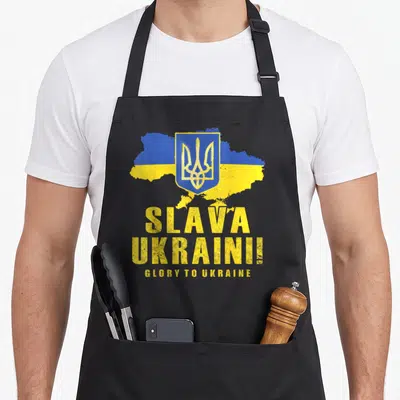 Tablier de cuisine noir avec carte Ukraine, trèfle doré et texte Slava Ukraini en lettres jaunes.