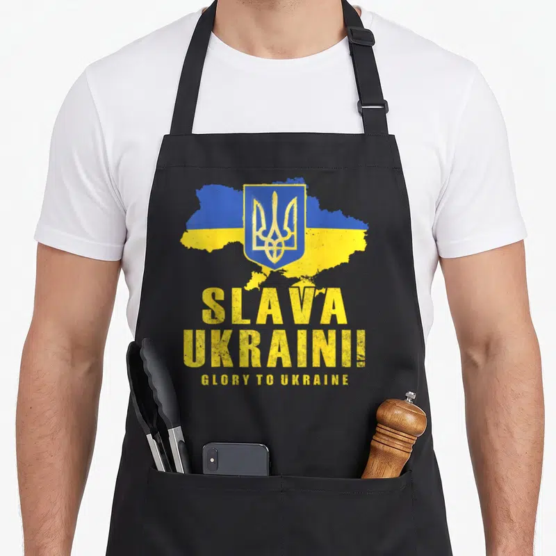Tablier de cuisine noir avec carte Ukraine, trèfle doré et texte Slava Ukraini en lettres jaunes.