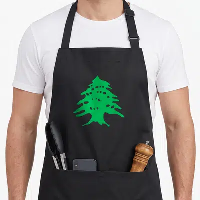 Tablier de cuisine noir avec un cèdre vert stylisé au centre, motif épuré sur fond sombre.