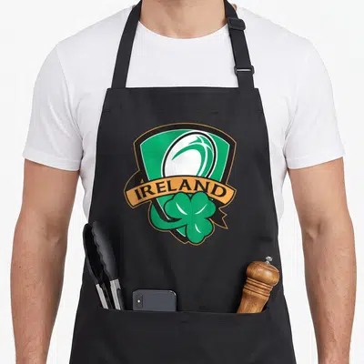 Tablier de cuisine noir avec logo Ireland Rugby, trèfle vert et ballon de rugby stylisé.