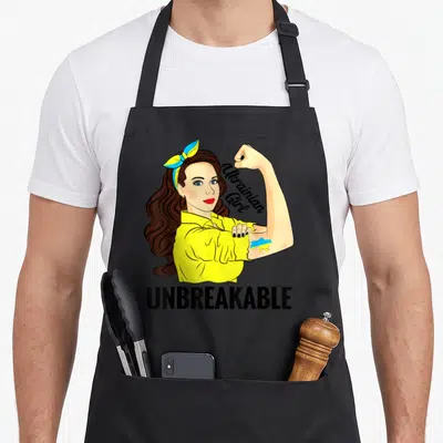 Tablier de cuisine noir avec illustration d'une Ukrainian Girl incassable et du drapeau de l'Ukraine sur le biceps.