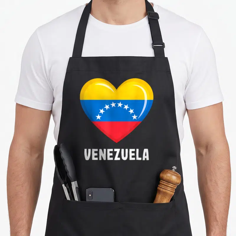 Tablier de cuisine noir avec un grand cœur stylisé aux bandes jaune bleu et rouge et le mot Venezuela en lettres blanches en dessous.