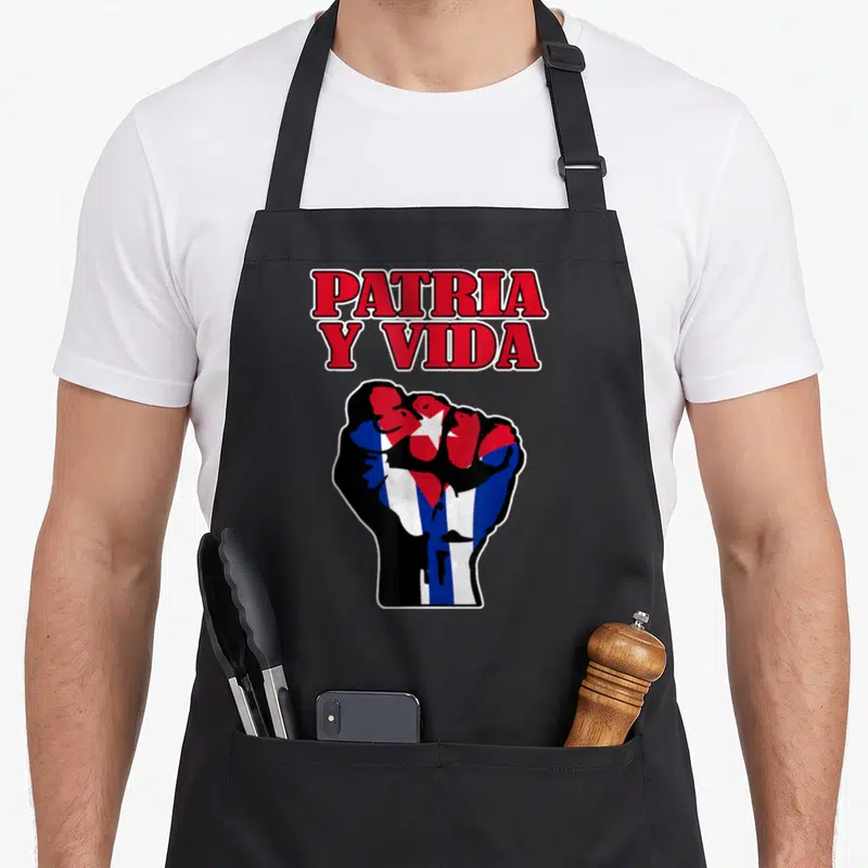 Tablier de cuisine noir avec un poing fermé orné du drapeau cubain et du texte Patria Y Vida en rouge.