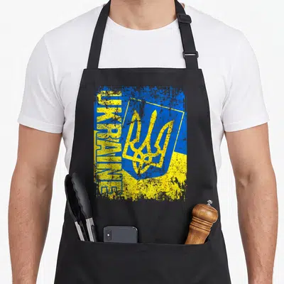 Tablier de cuisine noir avec le drapeau Ukraine, le trident et l'inscription UKRAINE en bleu et jaune texturé.