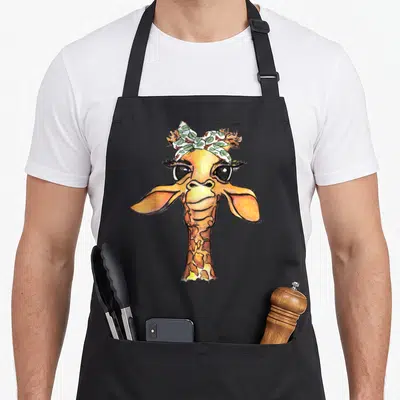 Tablier de cuisine noir avec une illustration de girafe hipster portant un bandana à motifs de feuilles vertes et blanches.