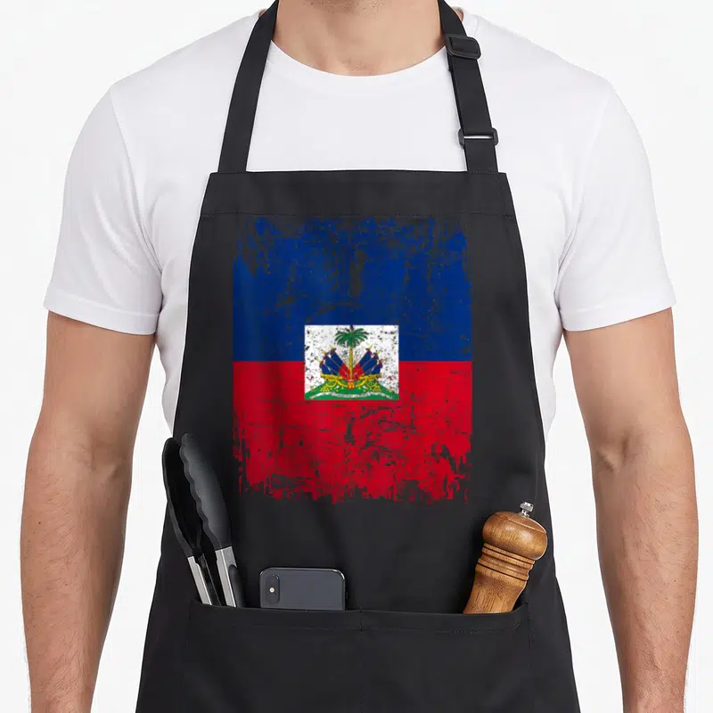 Tablier de cuisine noir avec drapeau Haïti style vintage et emblème central coloré.