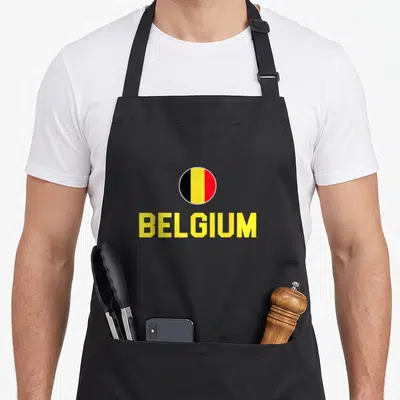 Tablier de cuisine noir avec un drapeau belge circulaire et le mot BELGIUM en jaune vif au centre.