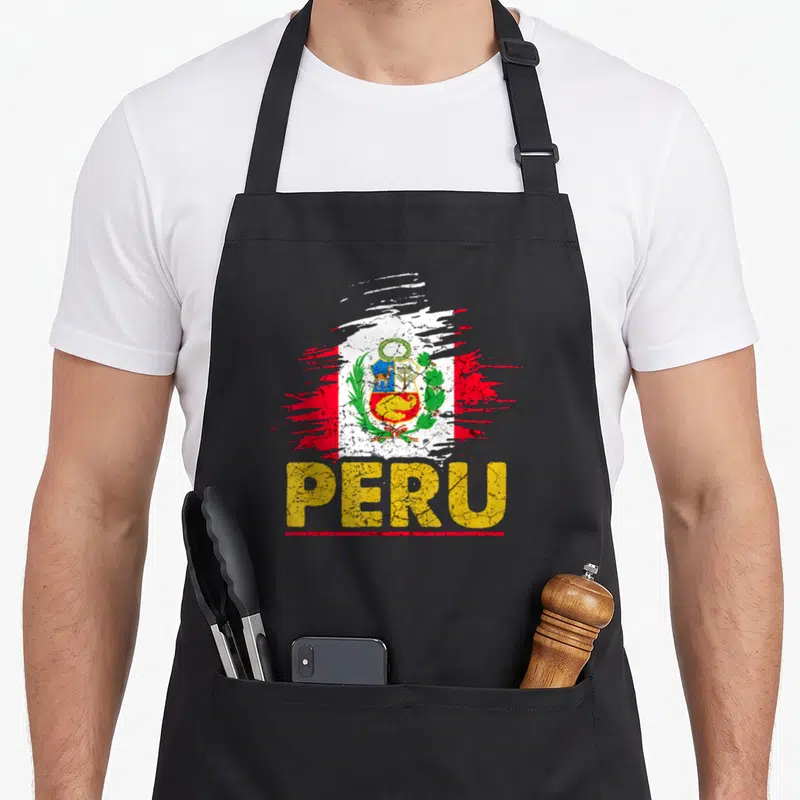 Tablier de cuisine noir avec drapeau Peru stylisé et le mot PERU en lettres jaunes craquelées au centre.