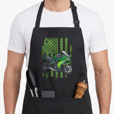 Tablier de cuisine noir avec illustration de moto sportive verte sur fond de drapeau américain déstructuré vert et gris.