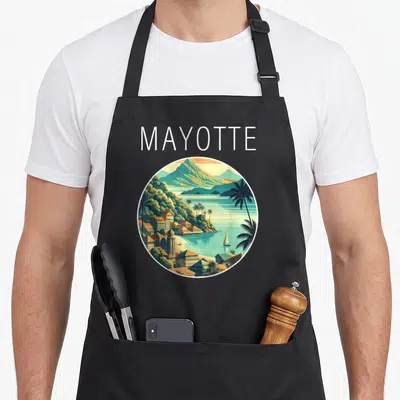 Tablier de cuisine noir avec illustration circulaire d'un paysage de Mayotte aux couleurs chaudes et palmiers.