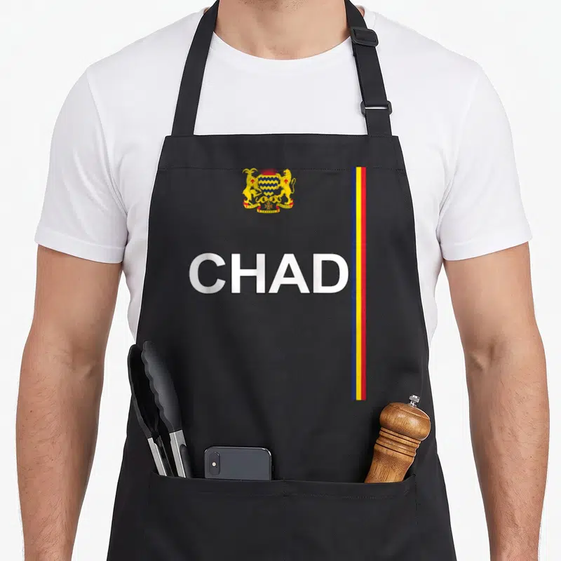 Tablier de cuisine noir avec CHAD, armoiries dorées et bandes verticales bleue jaune rouge sur la droite.