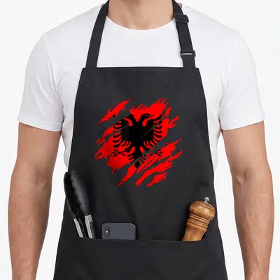 Tablier de cuisine noir avec aigle albanais rouge stylisé en éclat sur fond uni.