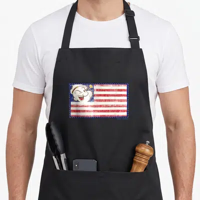 Tablier de cuisine noir avec illustration d'un drapeau patriotique et le visage souriant de Popeye en bordure bleue.