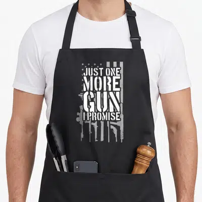 Tablier de cuisine noir avec inscription blanche et motifs d'armes formant un drapeau américain.