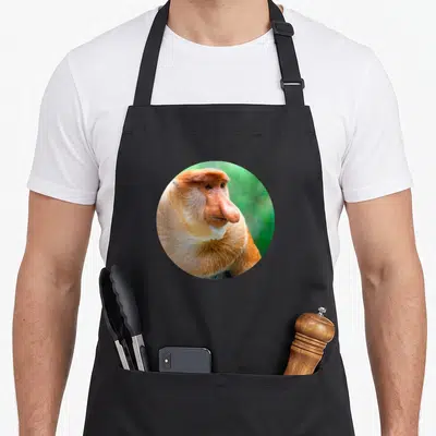 Tablier de cuisine noir avec portrait circulaire d'un singe proboscis au nez proéminent et pelage roux.