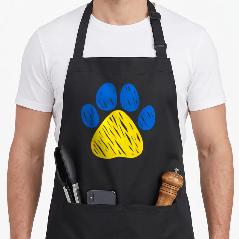 Tablier de cuisine noir avec une grande patte animalière bleue et jaune au centre.