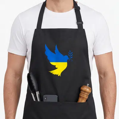 Tablier de cuisine noir avec une colombe bleue et jaune tenant une branche d'olivier.
