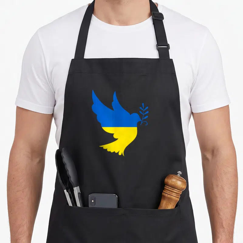 Tablier de cuisine noir avec une colombe bleue et jaune tenant une branche d'olivier.