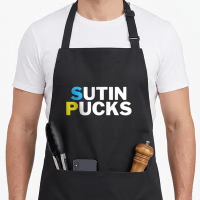 Tablier de cuisine noir avec inscription Sutin Pucks en bleu, blanc et jaune sur fond uni.