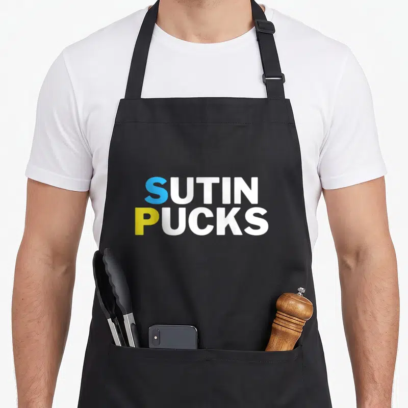 Tablier de cuisine noir avec inscription Sutin Pucks en bleu, blanc et jaune sur fond uni.