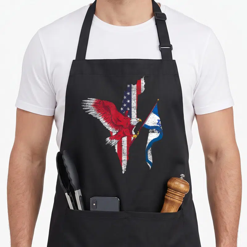 Tablier de cuisine noir avec aigle aux ailes rouges tenant un drapeau israélien sur une silhouette américaine texturée.