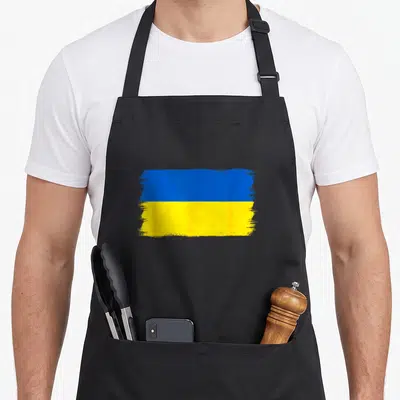 Tablier de cuisine noir avec un drapeau Ukraine peint en bleu et jaune au centre.