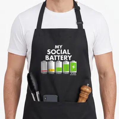 Tablier de cuisine noir avec illustration de batteries sociales colorées et texte blanc My Social Battery With Gens.