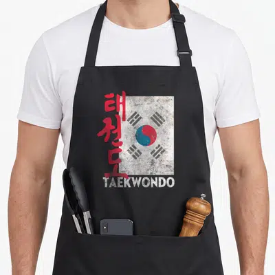 Tablier de cuisine noir avec drapeau coréen, calligraphie rouge et inscription TAEKWONDO en bas.