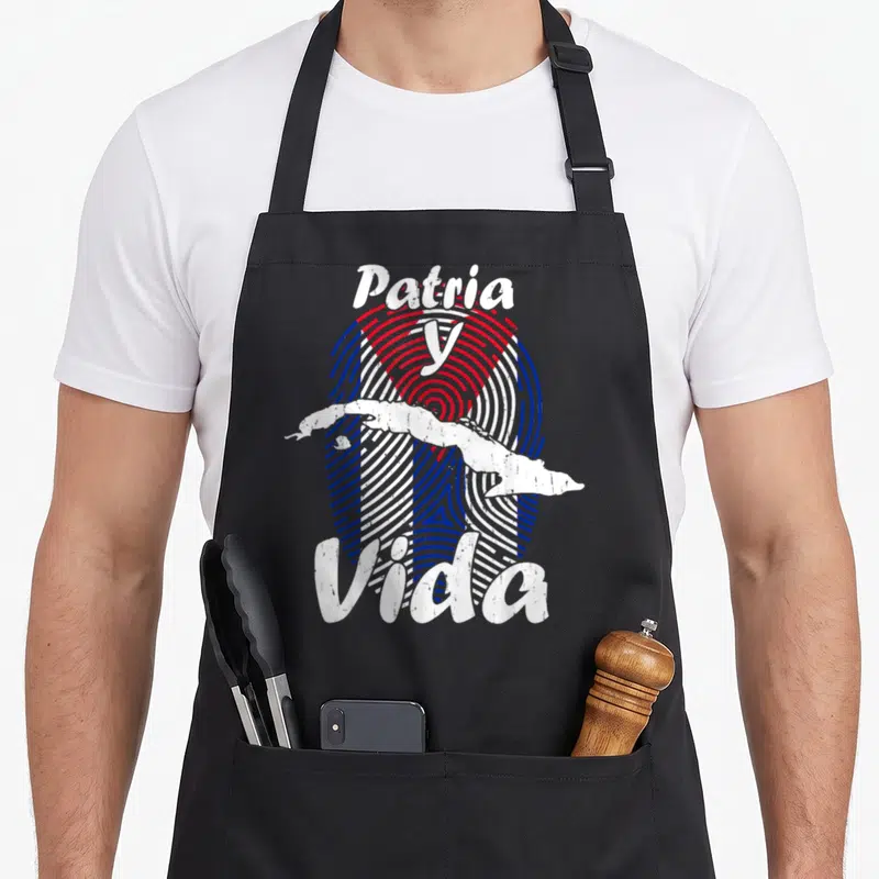 Tablier de cuisine noir avec l'inscription Patria y Vida superposée à une carte de Cuba et des lignes concentriques colorées.