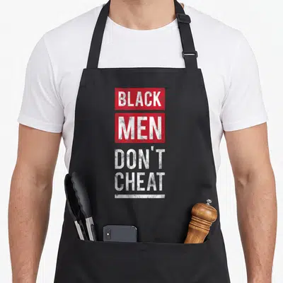 Tablier de cuisine noir avec inscription Black Men Don't Cheat en lettres blanches sur fond rouge et gris.