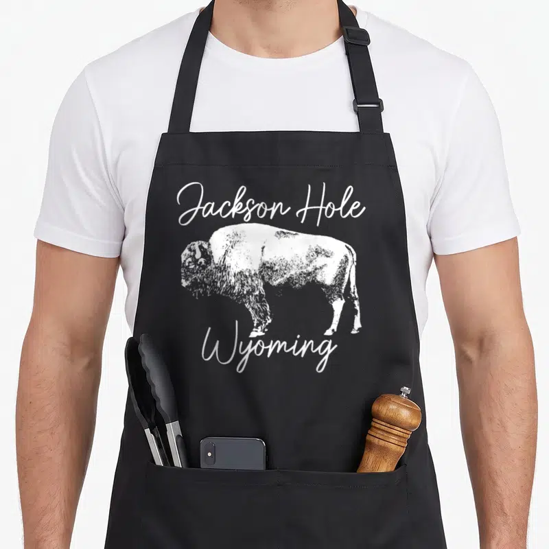 Tablier de cuisine noir avec illustration d'un bison et texte Jackson Hole Wyoming en blanc.