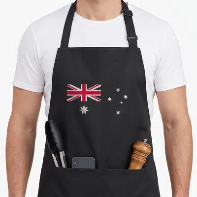 Tablier de cuisine noir avec illustration du drapeau australien, Union Jack et étoiles blanches sur fond uni.