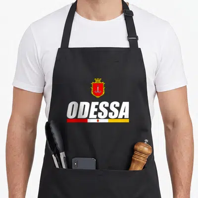 Tablier de cuisine noir avec le mot ODESSA, un blason à l'ancre et une bande tricolore rouge blanc jaune.