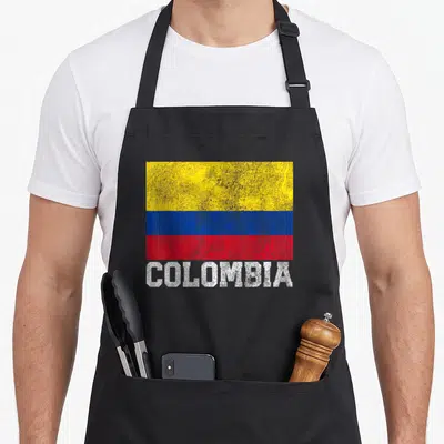 Tablier de cuisine noir avec le drapeau colombien et l'inscription COLOMBIA en lettres blanches texturées.
