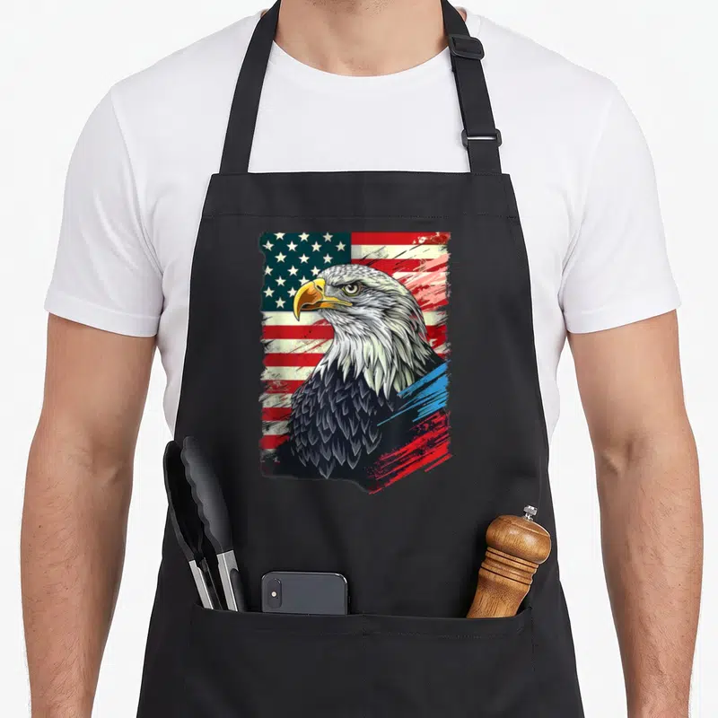 Tablier de cuisine noir avec illustration de pygargue à tête blanche sur drapeau américain aux couleurs vives et style graffiti.