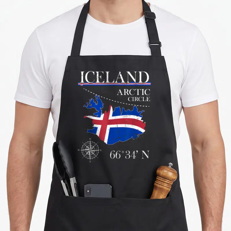 Tablier de cuisine noir avec une carte d'Islande aux couleurs du drapeau et un compas en bas à gauche.