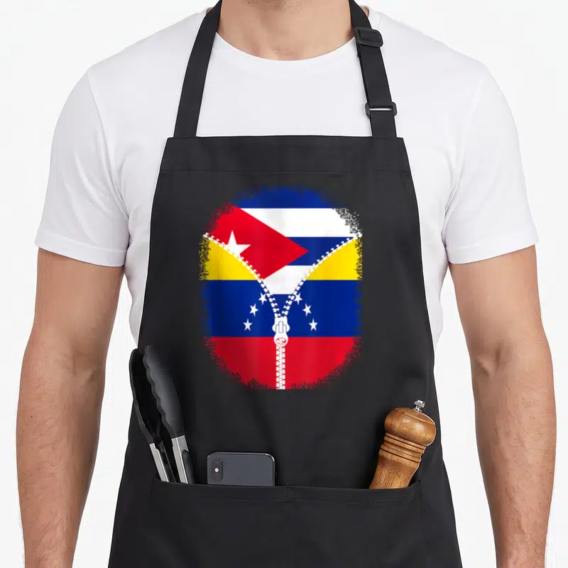 Tablier de cuisine noir avec un drapeau cubain et vénézuélien séparés par une fermeture éclair blanche.